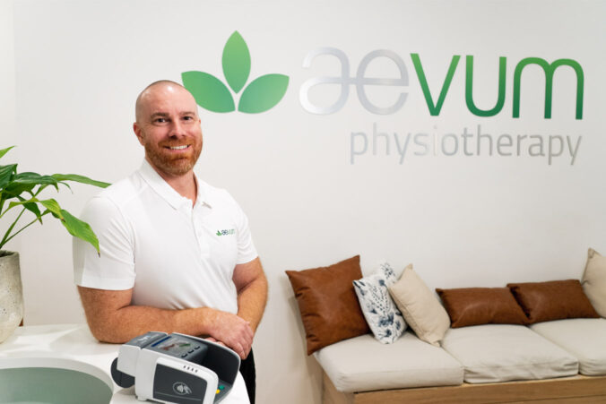 Aevum employee smiling at the camera with a Tyro EFTPOS machine standing in front of him