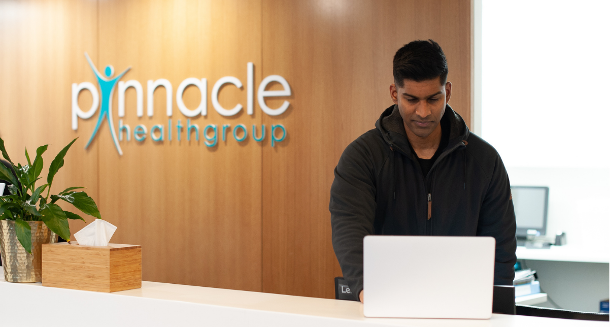 Employee behind counter typing something into a computer.