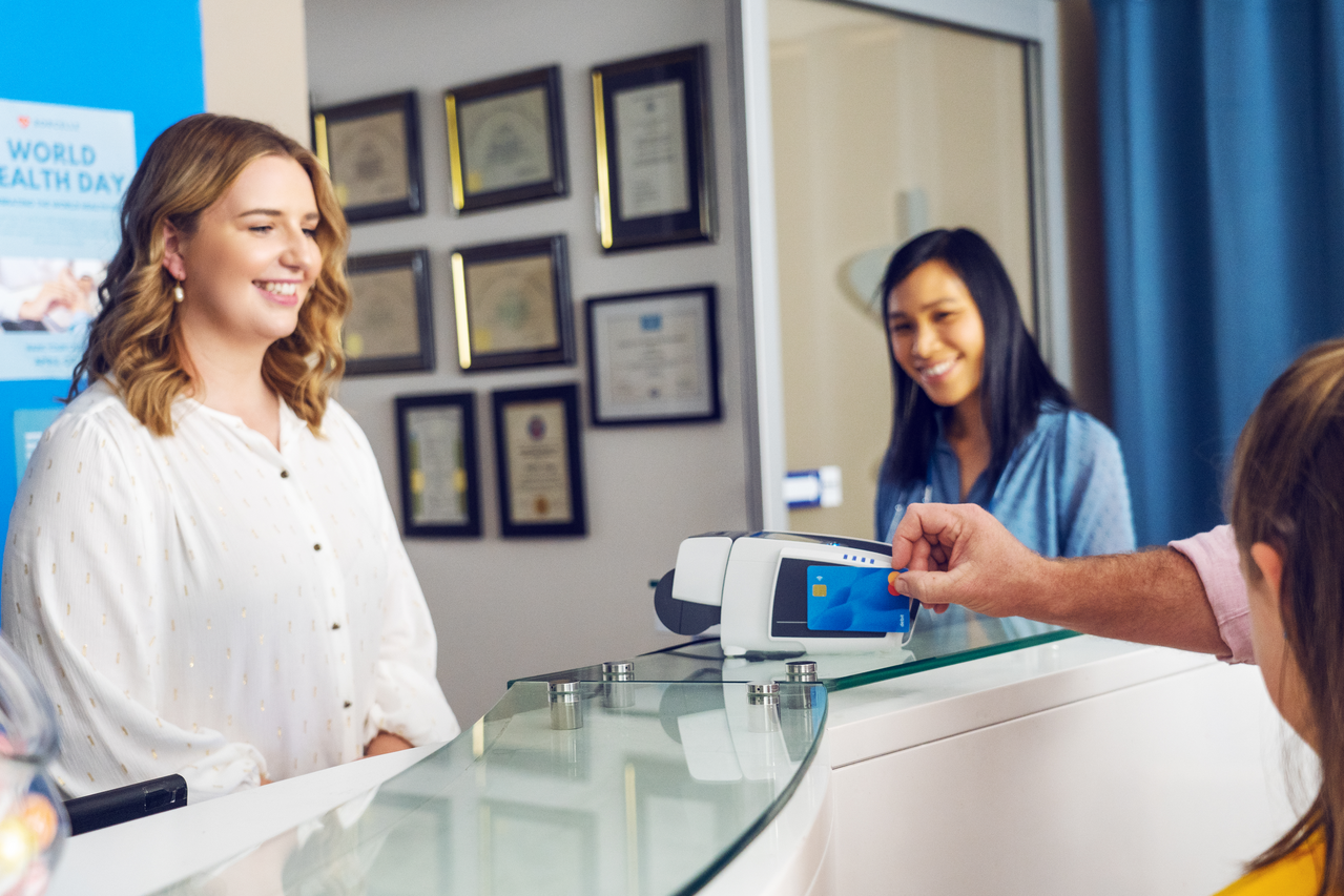 Practice reception with a patient paying on a countertop EFTPOS