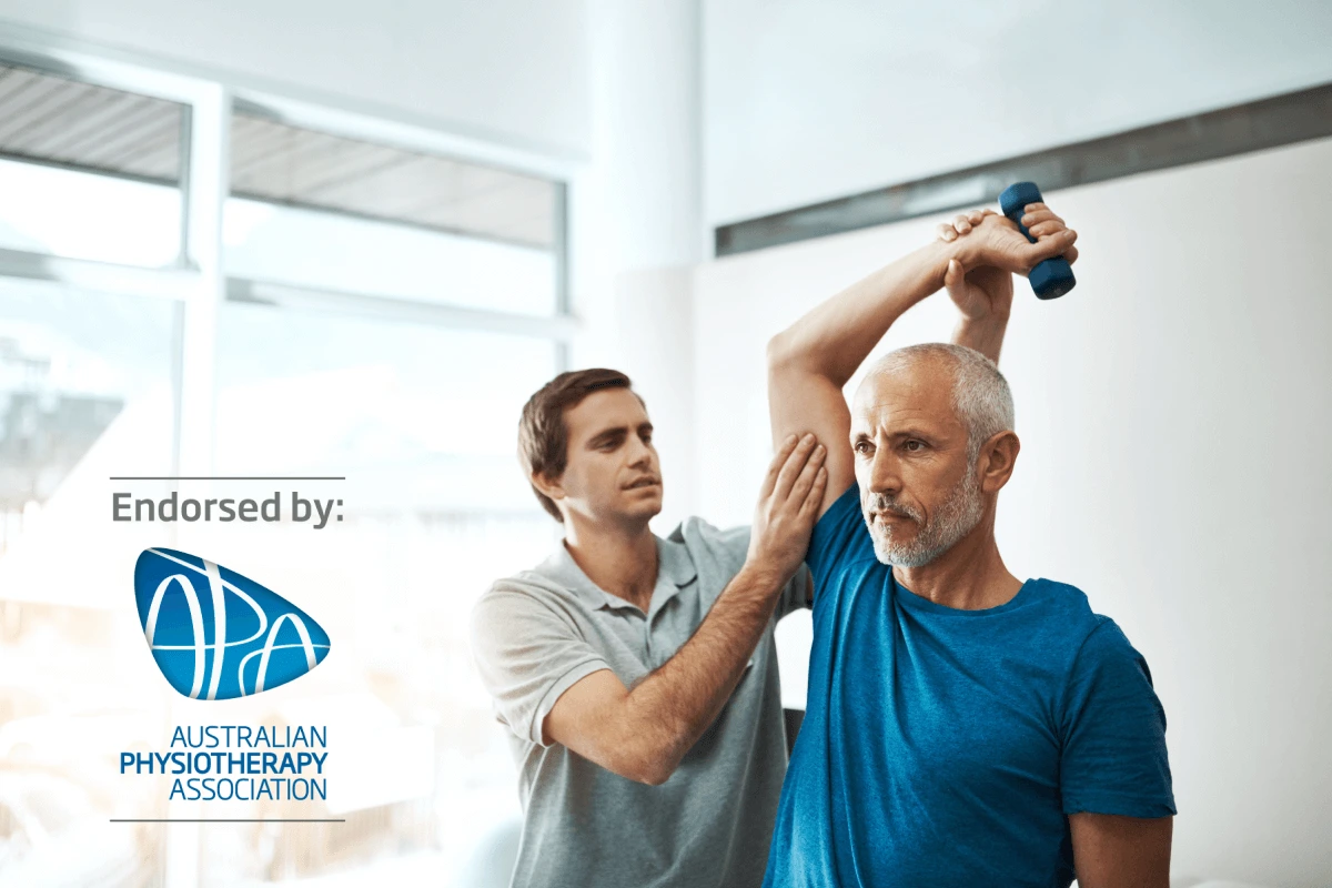 Friendly physio treating his male client in a physio studio, showing endorsed by the Australian Physio Association (APA) logo in the bottom left corner of the image.
