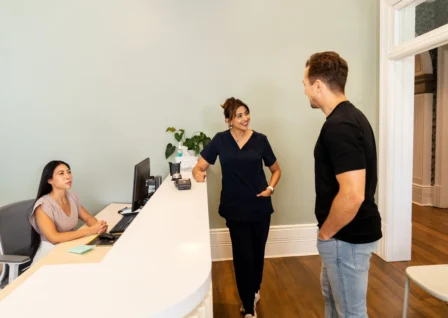 Receptionist and healthcare provider speaking with a patient at the front desk of a modern Australian medical practice