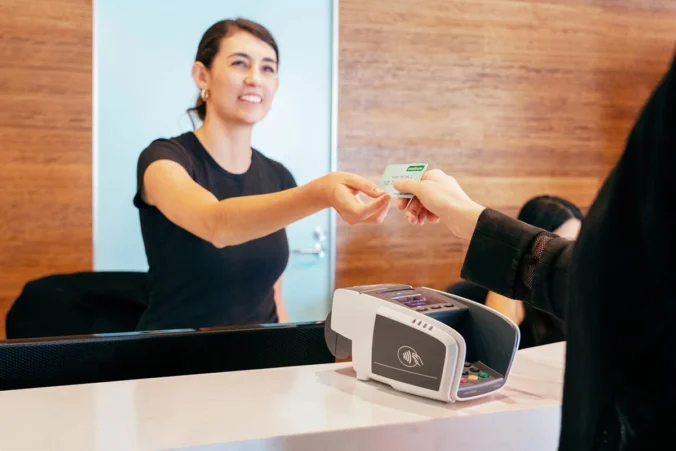 Healthcare receptionist assisting patient with secure EFTPOS card payment at front desk in Australia - Tyro Health