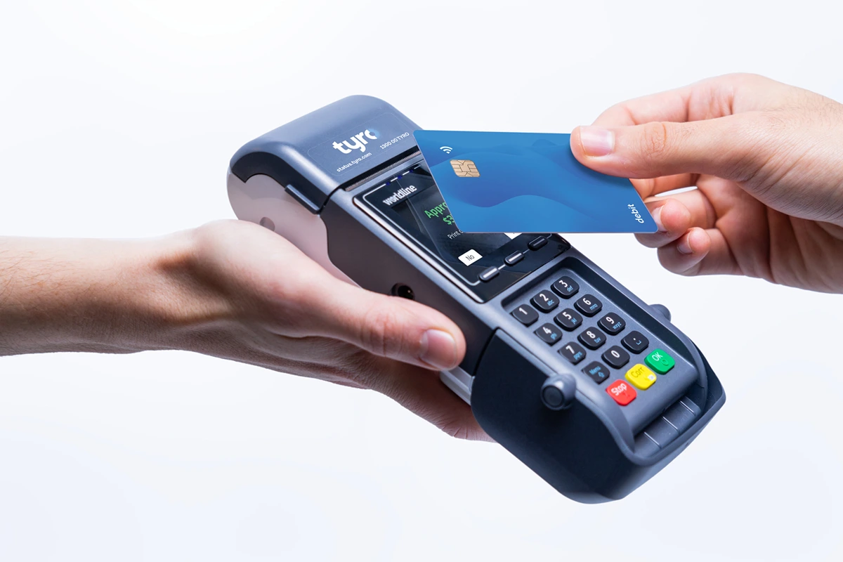 Patient tapping a debit card on a Tyro Health Mobile EFTPOS terminal for contactless payment